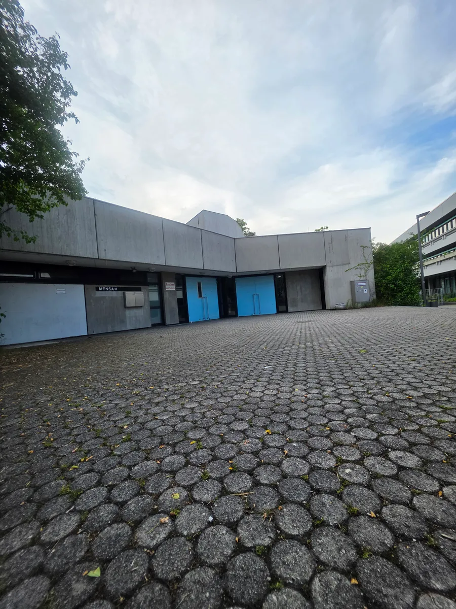 Mensa des Schulzentrums – Sichtbetonbau mit blauen Türen